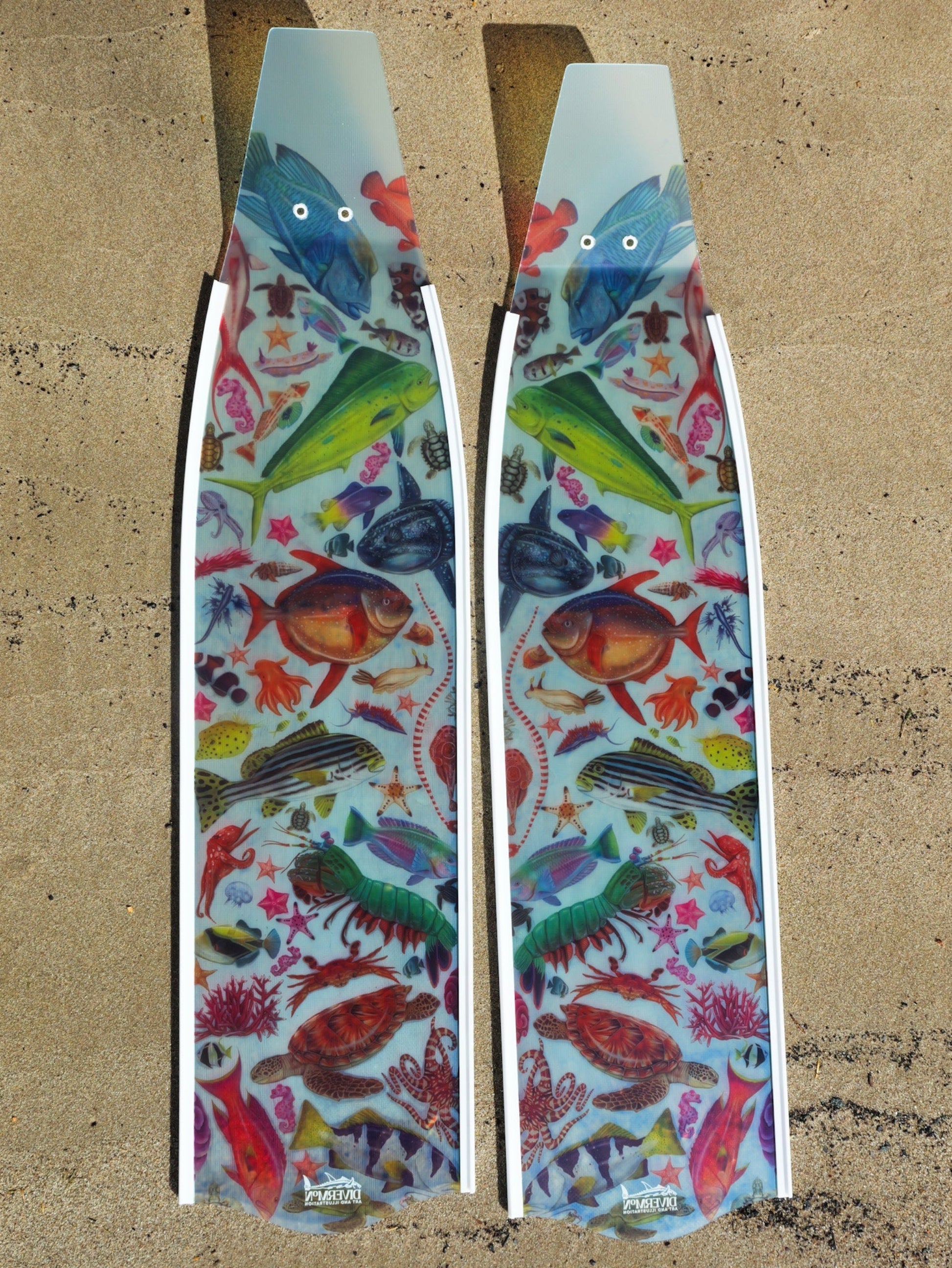 Two colorful fish-patterned surfboard fins on a textured surface